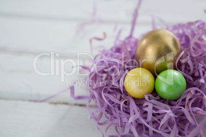 Golden Easter egg with two painted eggs in nest