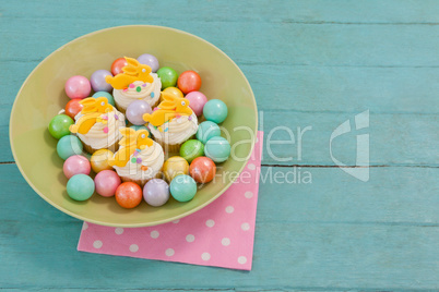 Colorful chocolates and cupcakes in bowl