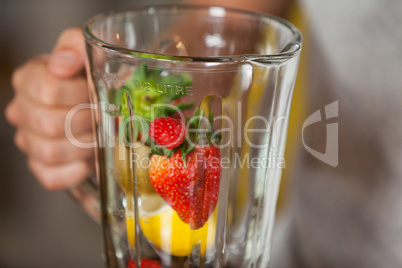 Male staff holding juice mixer with various fruits