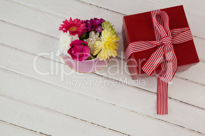 Gift box and fresh flowers on wooden surface