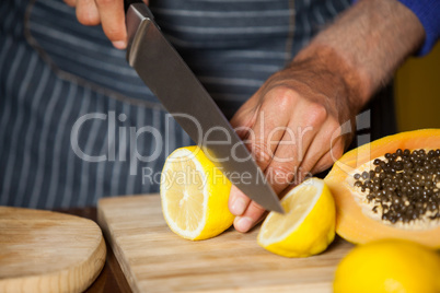 Mid-section of male staff cutting lemon in organic section