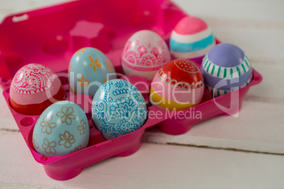 Multicolored Easter eggs in the pink carton