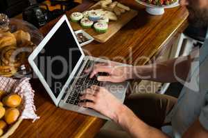 Man using laptop at counter in coffee shop