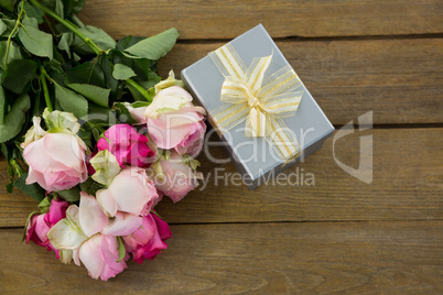 Gift box with bunch of rose on wooden plank