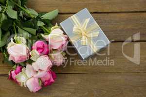 Gift box with bunch of rose on wooden plank
