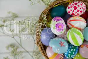 Basket with painted Easter eggs on wooden background