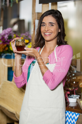 Smiling shop assistant holding a jar of pickle