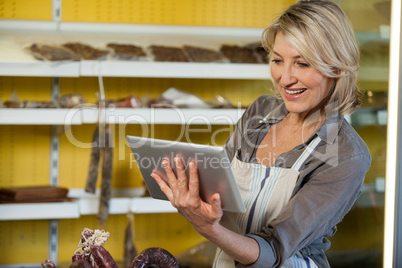 Smiling female staff using digital tablet at counter
