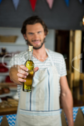 Smiling shop assistant holding olive oil bottle