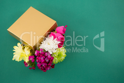 Gift box full of flower against green background