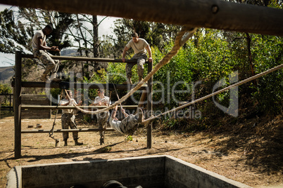 Young military soldiers practising rope climbing during obstacle course