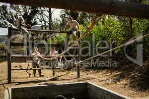 Young military soldiers practising rope climbing during obstacle course