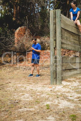 Man standing while woman sitting over wooden wall