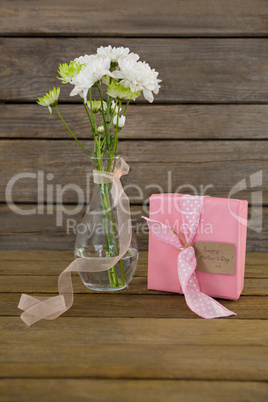 Gift box and flower vase on wooden surface