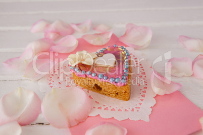 Heart shape gingerbread cookie with petals on table
