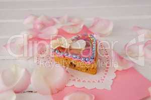 Heart shape gingerbread cookie with petals on table