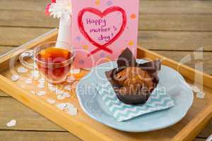 Cupcake, tea, flower vase and happy mothers day greetings card in tray