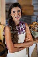 Portrait of smiling female staff standing with arms crossed at bakery shop