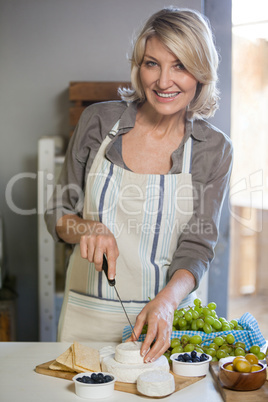 Portrait of female staff slicing cheese at counter