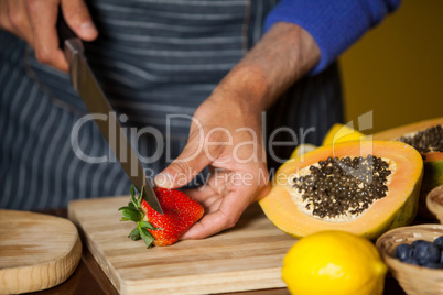 Mid-section of male staff cutting strawberry at organic section