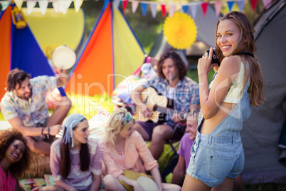 Portrait of woman taking a picture of friends at campsite