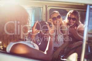 Woman taking photograph of friends in campervan