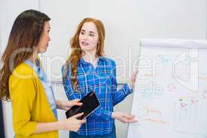 Colleagues discussing over flip chart board in conference room