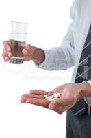 Businessman holding glass of water and medicines