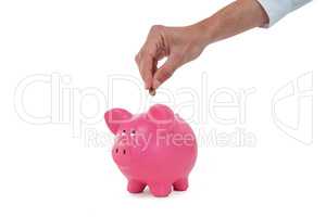 Hand inserting coin in piggy bank