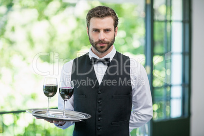 Male waiter holding tray with wine glasses