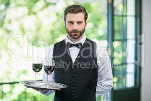 Male waiter holding tray with wine glasses