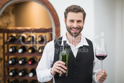 Male waiter holding wine glass and wine bottle in the restaurant