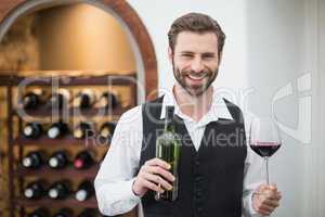 Male waiter holding wine glass and wine bottle in the restaurant