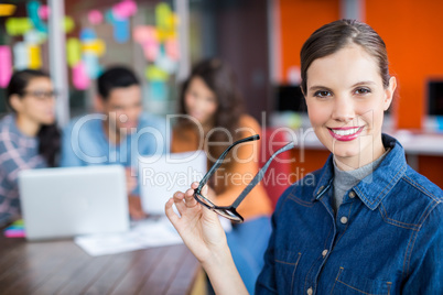 Portrait of smiling female executive standing with spectacles