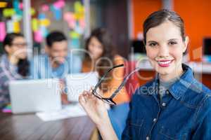 Portrait of smiling female executive standing with spectacles