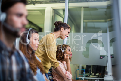 Female customer service executive interacting with her colleague at desk