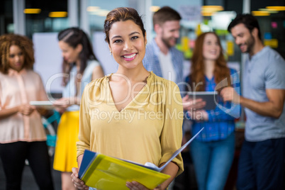 Portrait of smiling female executive holding clipboard and file