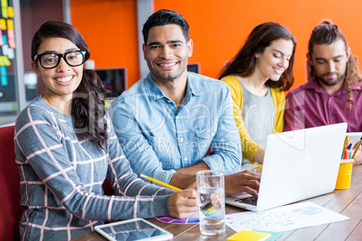 Smiling graphic designers discussing over laptop in meeting