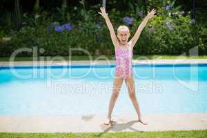 Girl standing with her hands raised near swimming pool