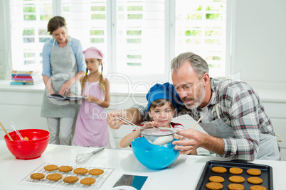 Father and son preparing cookies in kitchen