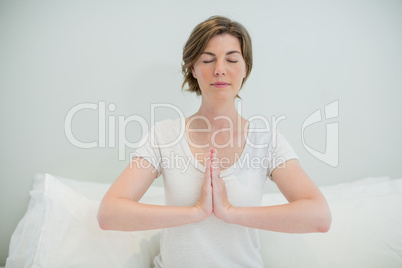 Woman doing meditation on bed in bedroom