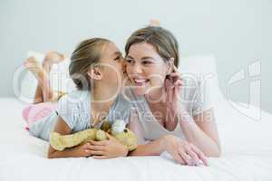 Adorable girl kissing her mother lying on a bed