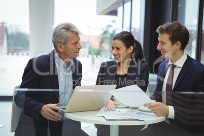 Business people discussing over laptop