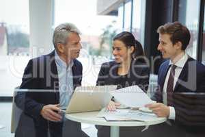 Business people discussing over laptop