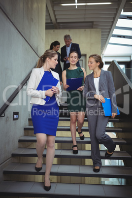 Businesspeople interacting with each other while walking downstairs