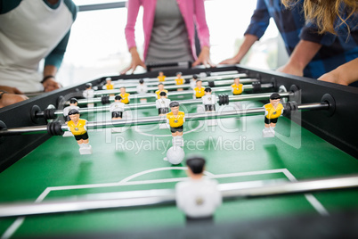 Mid section of executives playing table football