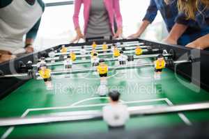 Mid section of executives playing table football