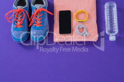 Sneakers, water bottle, towel, mobile phone with headphones and fitness band