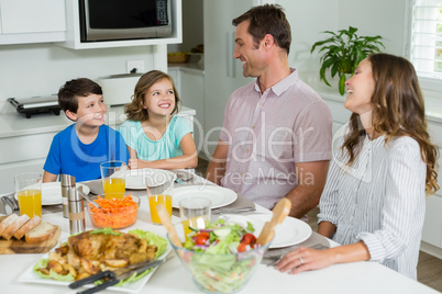 Smiling family interacting with each other while having lunch together