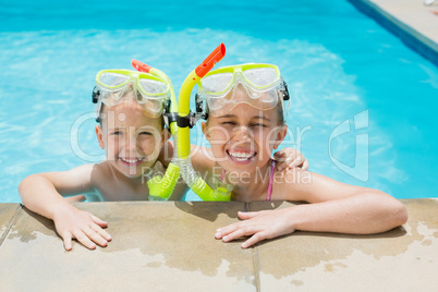 Smiling boy and girl relaxing on the side of swimming pool